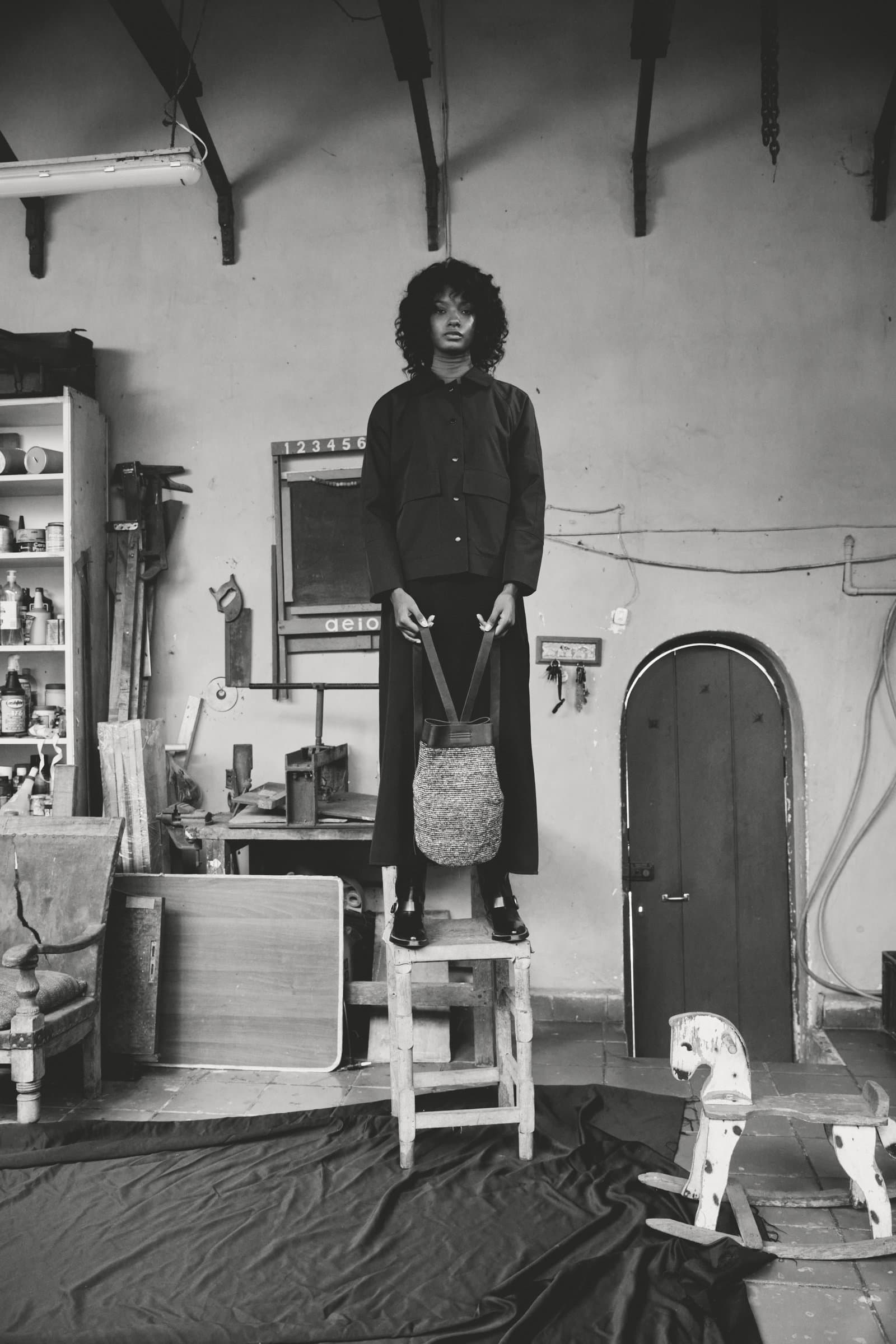 Modelo de pie sobre taburete, interior en blanco y negro