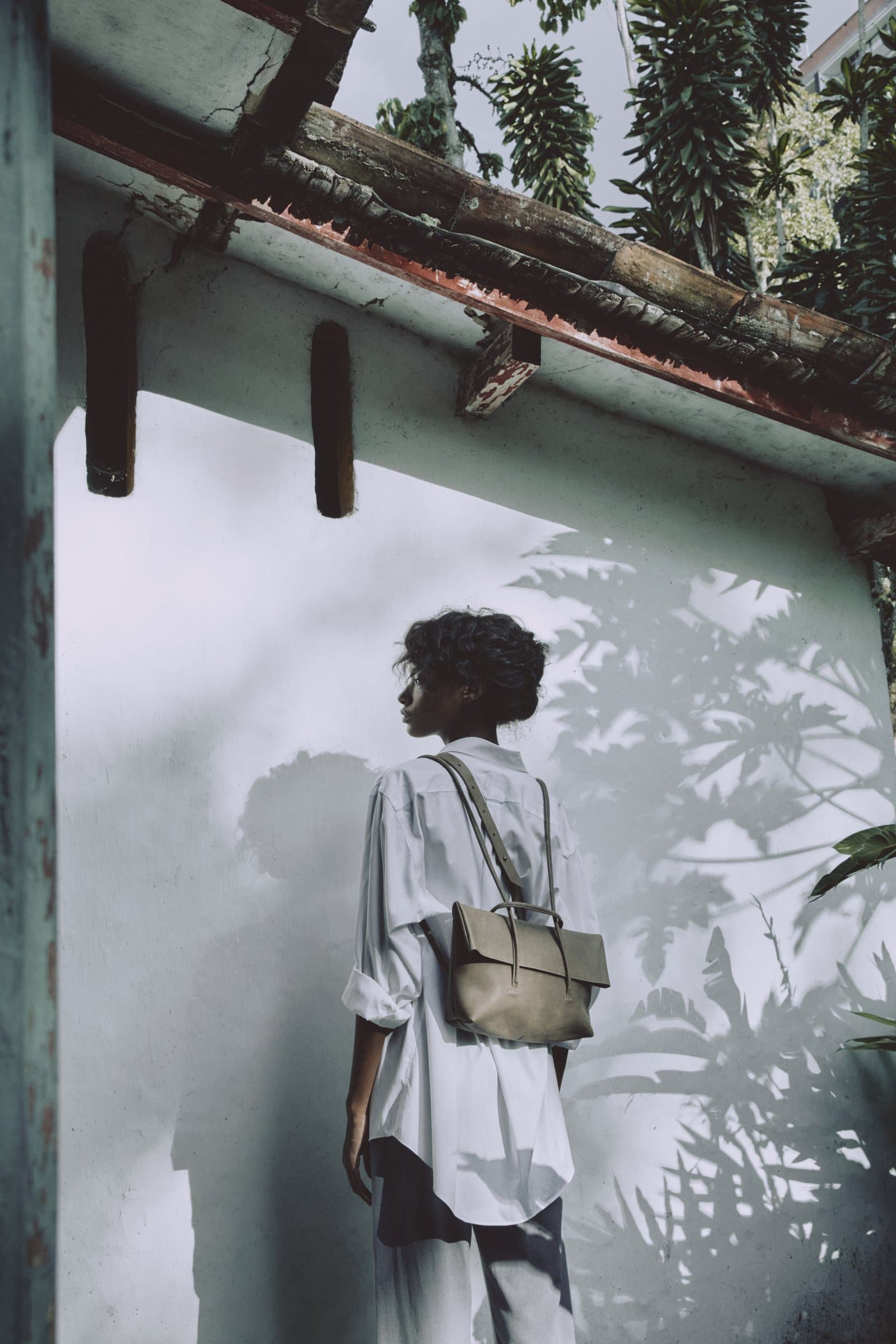 Modelo con bolso junto a muro con sombras de hojas