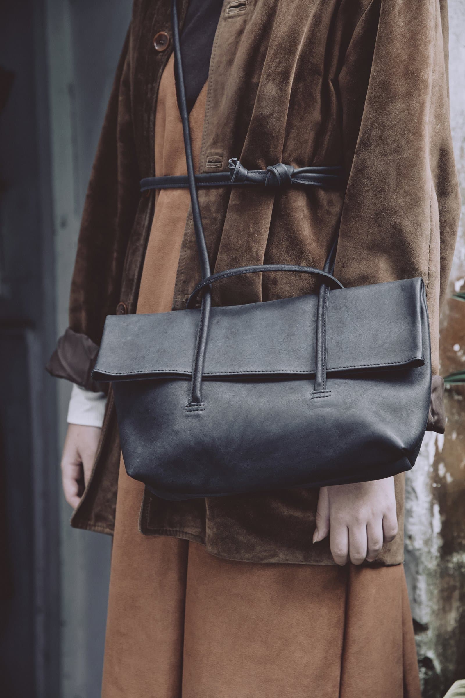 Bolso de cuero negro sobre abrigo café
